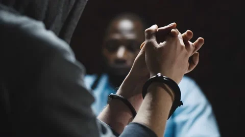 A man in handcuffs during police interrogation, wondering about the importance of Miranda Rights in Maryland.